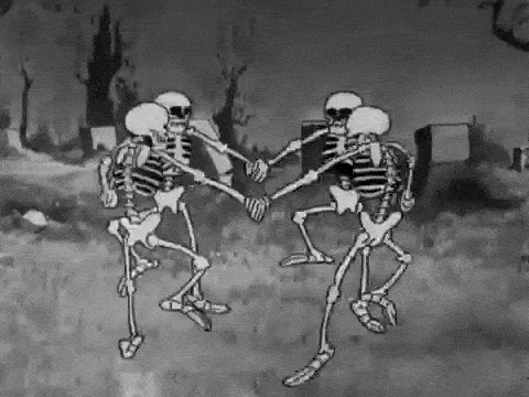 Skeletons dancing in a graveyard.