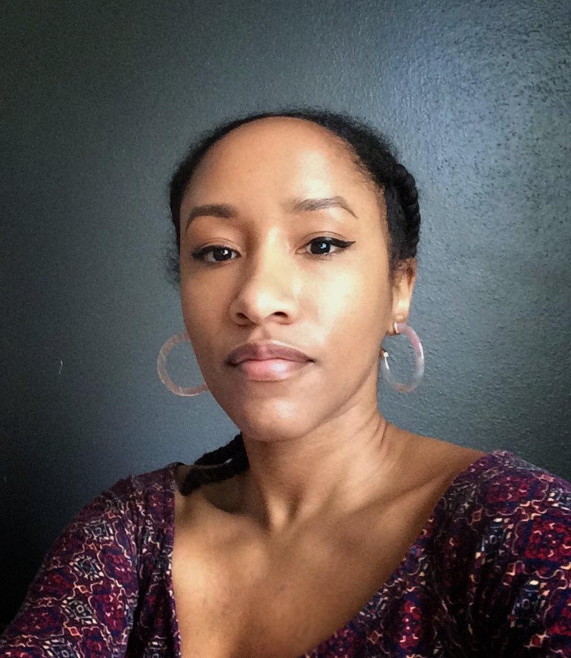 A woman wearing a purple shirt and hoop earrings.