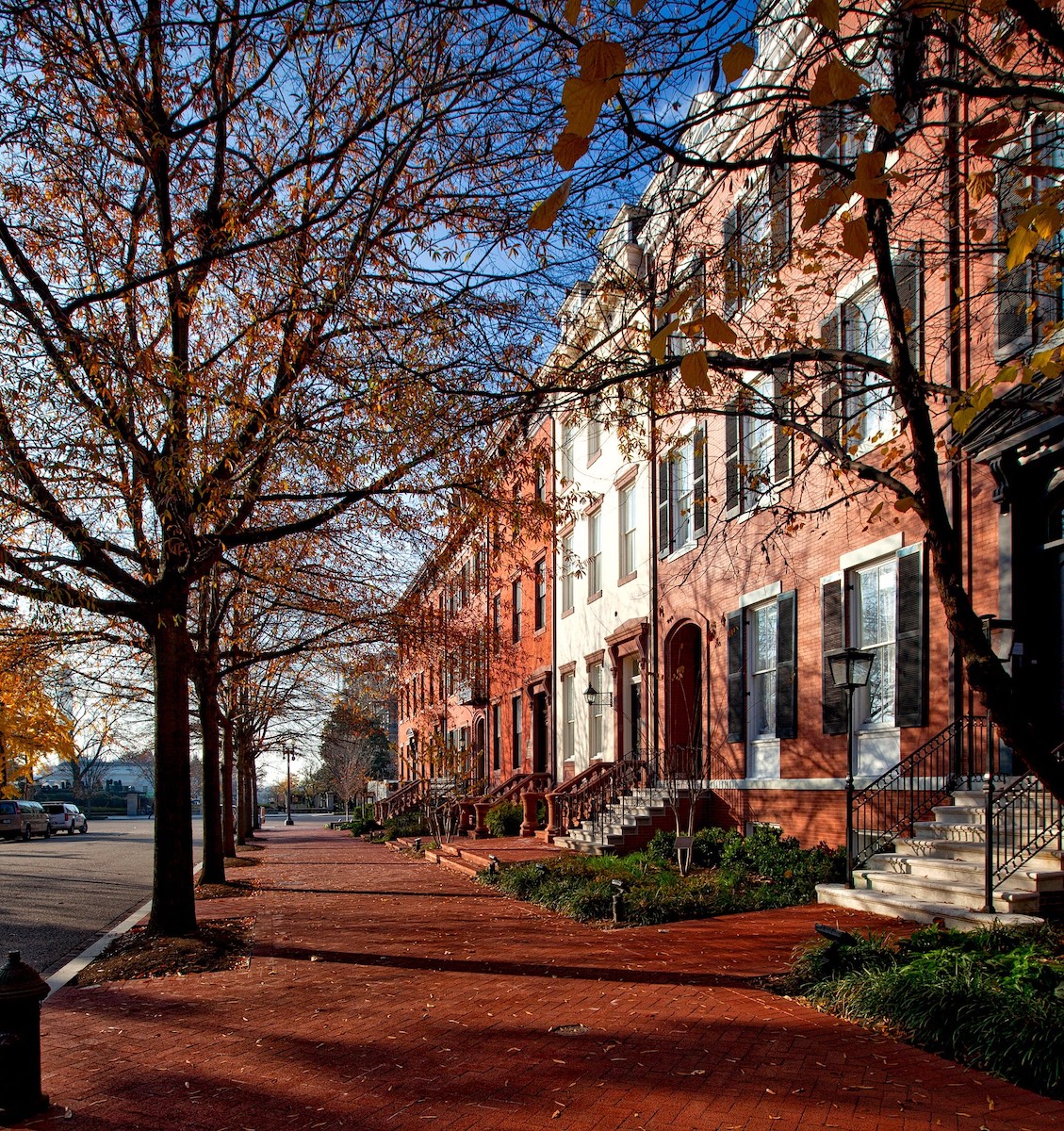 A row of red brick townhouses on a brick sidewalk.