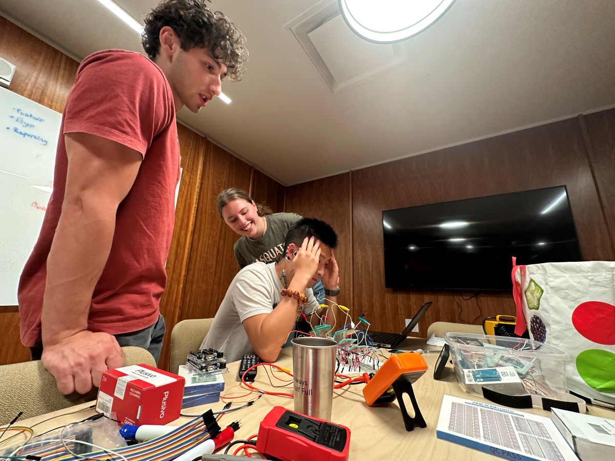 A group of people working on electronics in a room.
