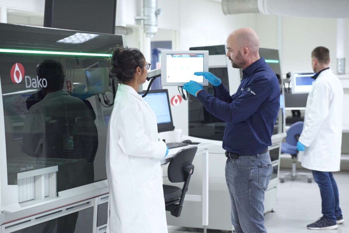 Two people in lab coats looking at a machine.