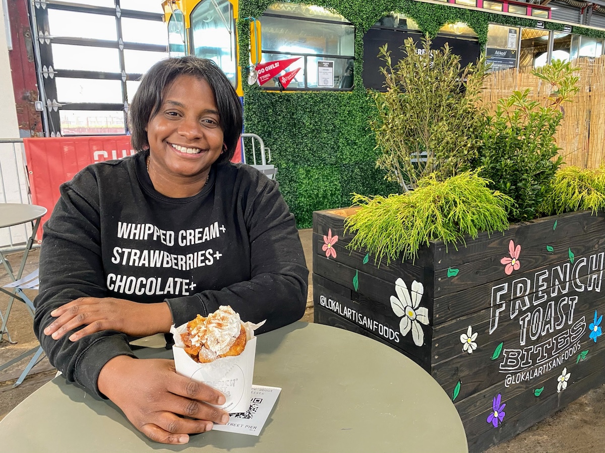 A smiling woman sitting at a table with a plate of food.