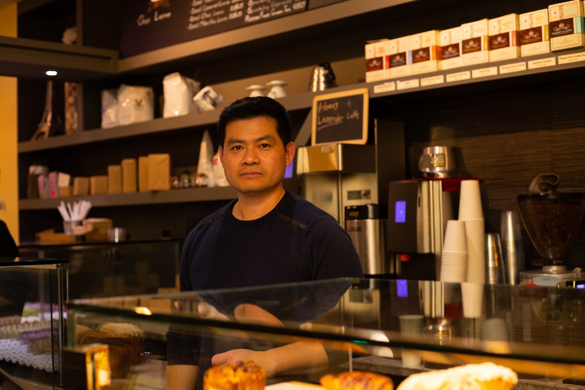 A man standing behind a counter in a coffee shop.