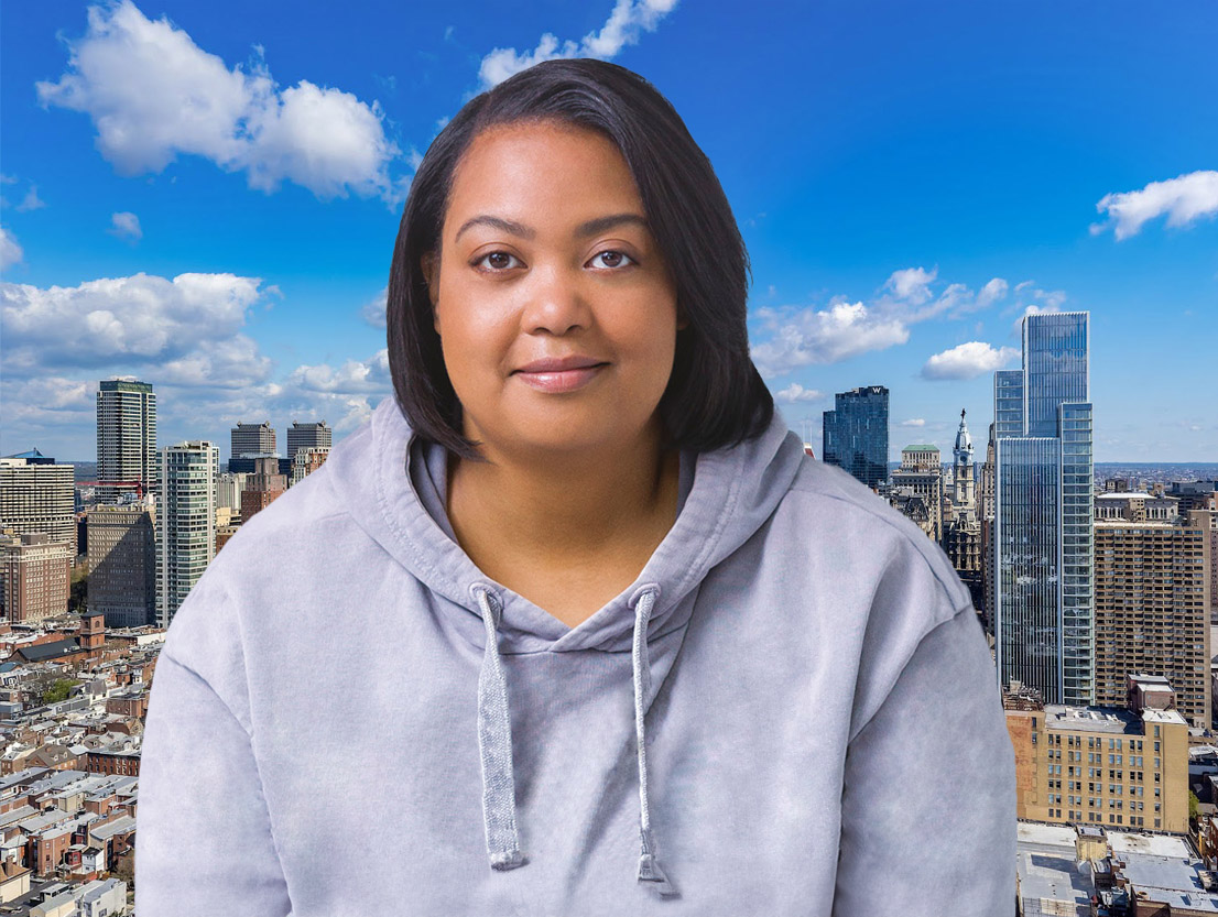 A woman in a gray hoodie standing in front of a city skyline.