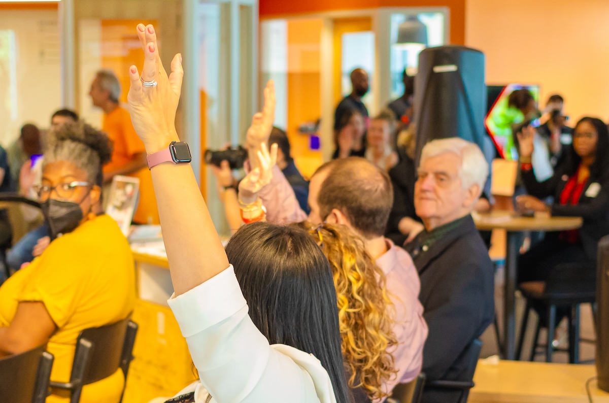 A group of people raising their hands in a room.