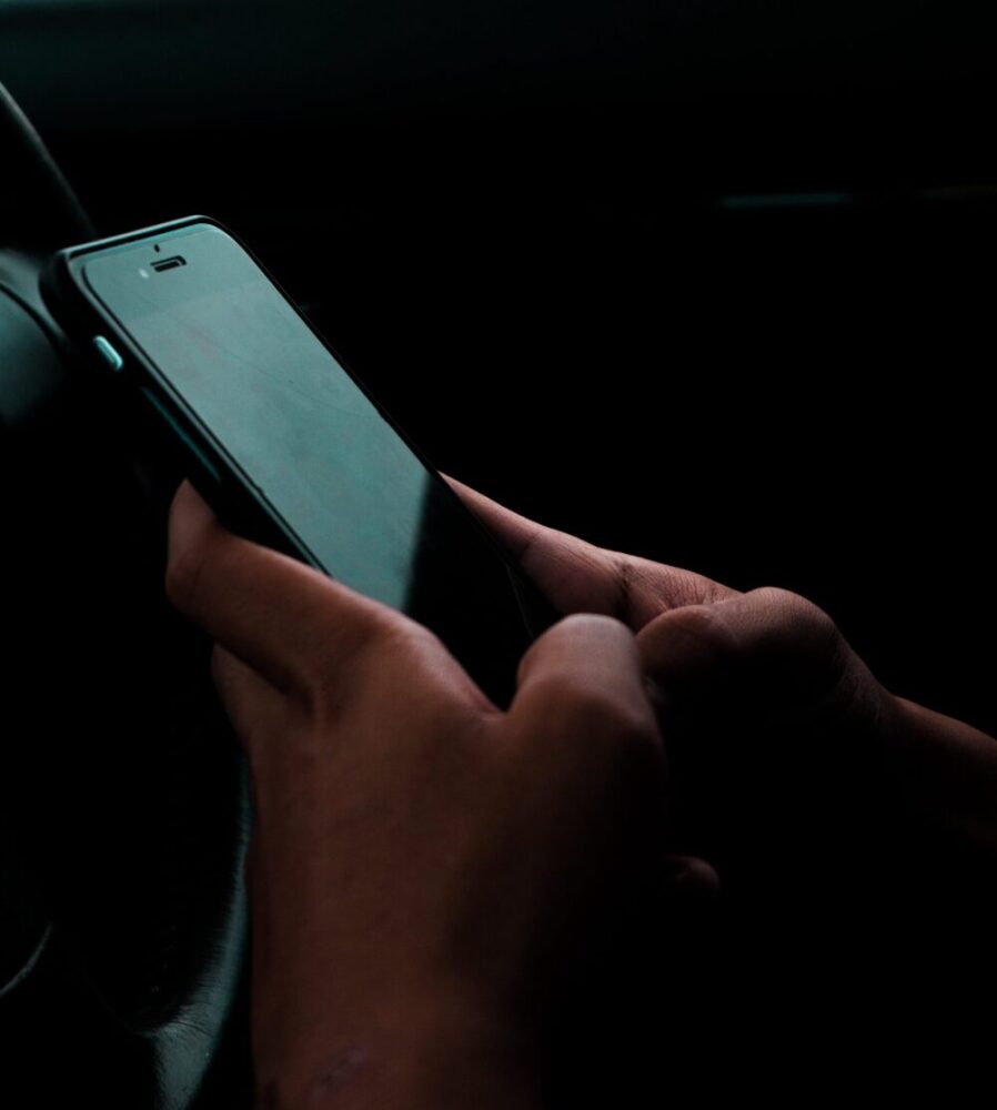 A person's hand holding a cell phone in a dark room.