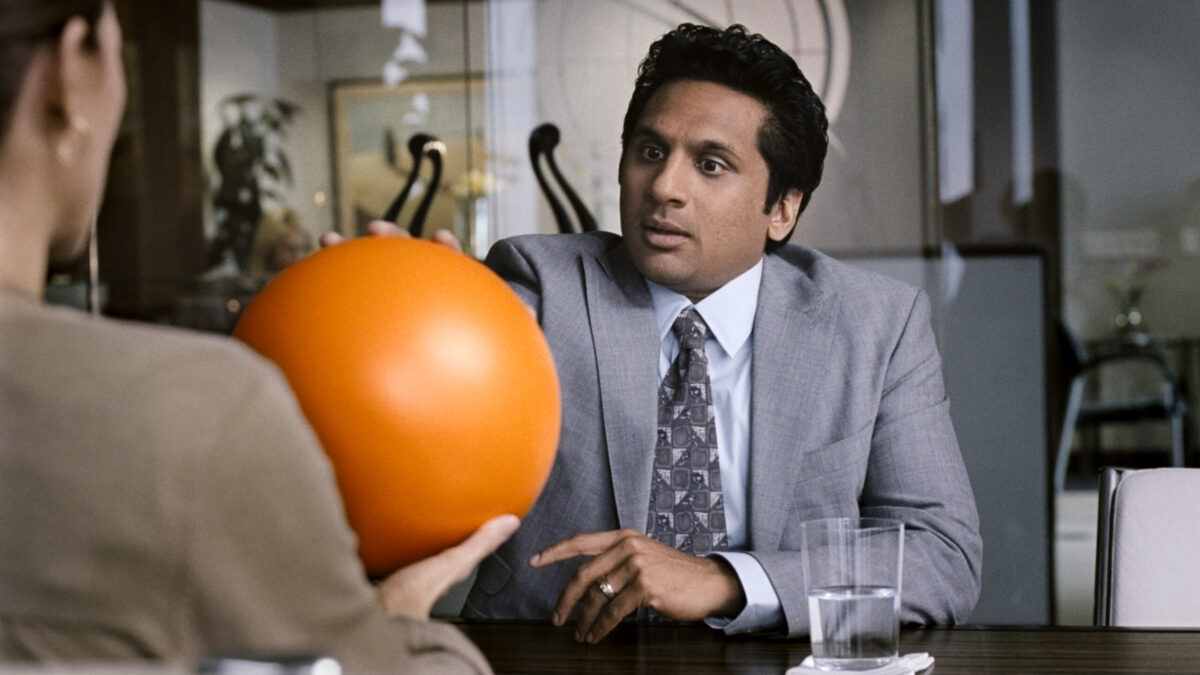 A man and woman sitting at a table holding an orange ball.