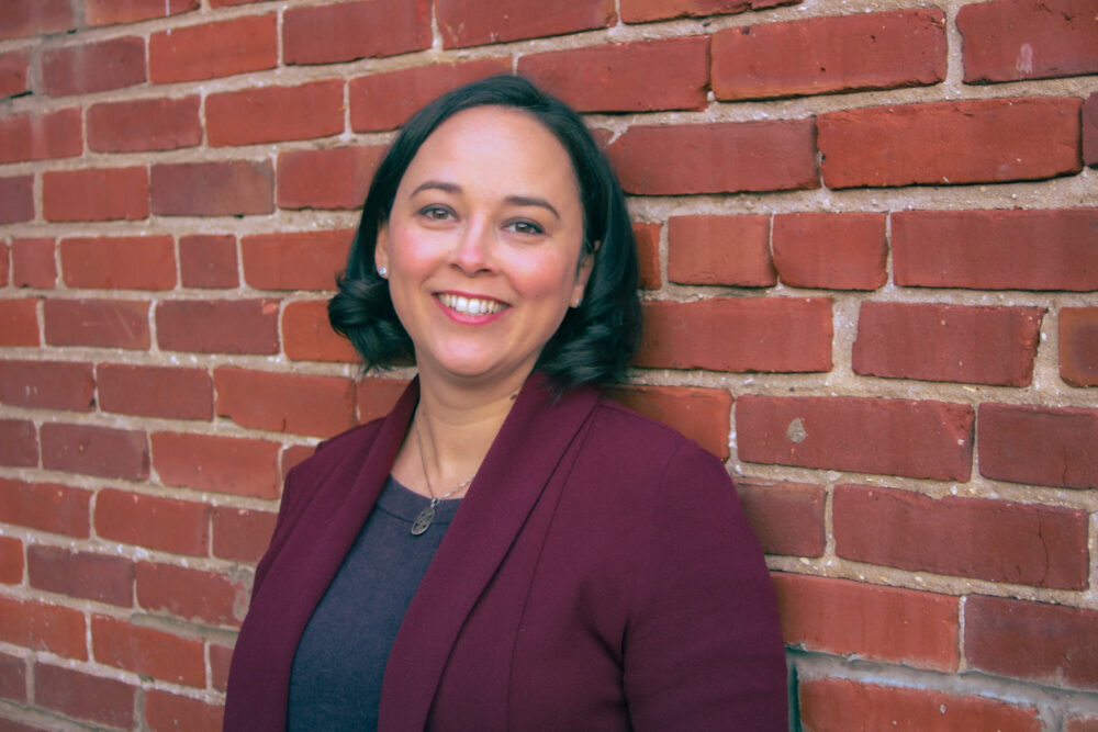 A woman leaning against a brick wall.
