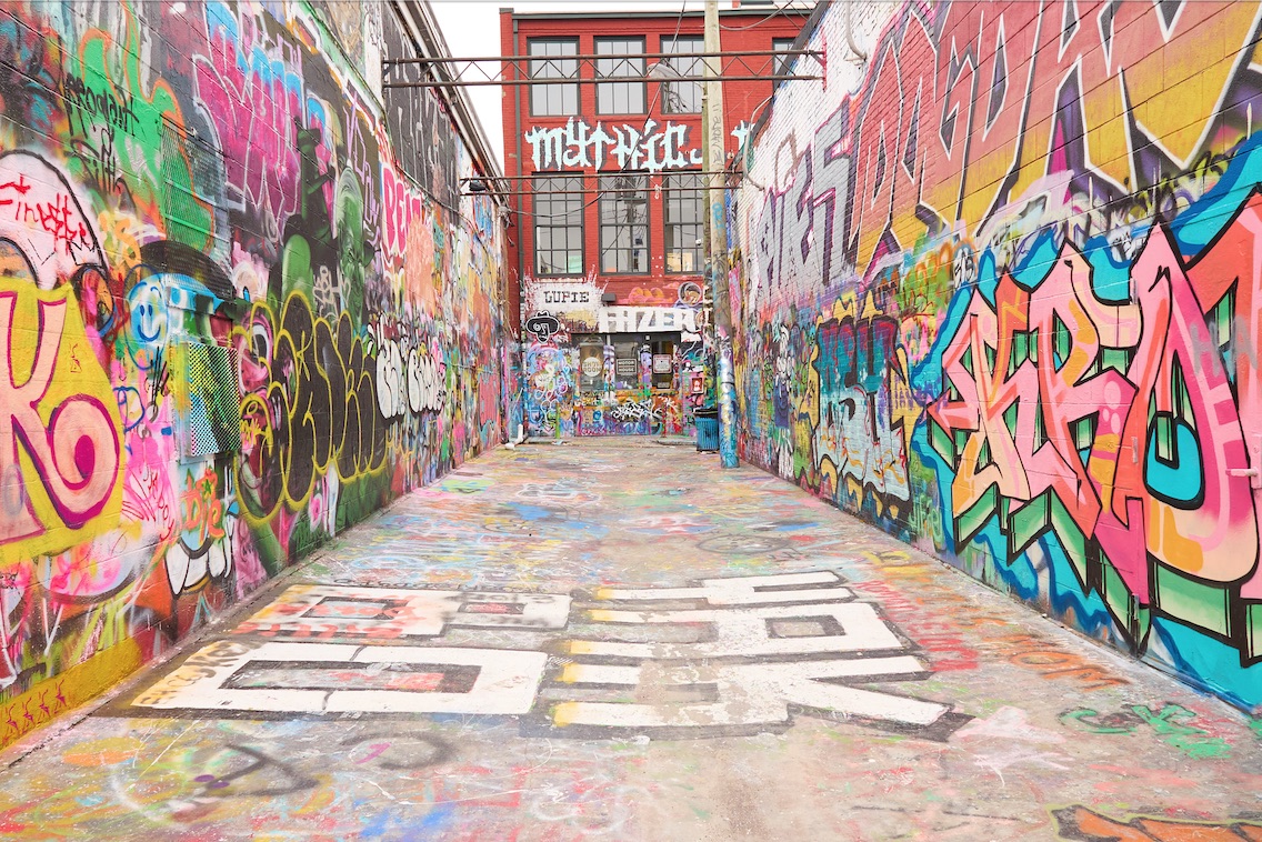 A narrow alley covered in colorful graffiti in Baltimore.