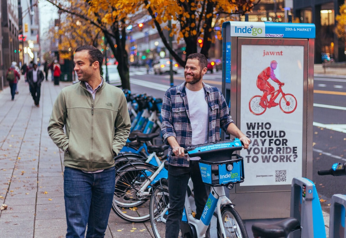Two men standing next to a bike rack.