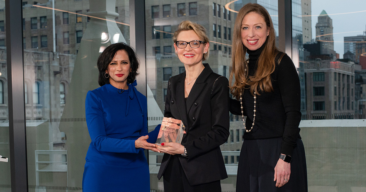 Three women standing next to each other holding an award.