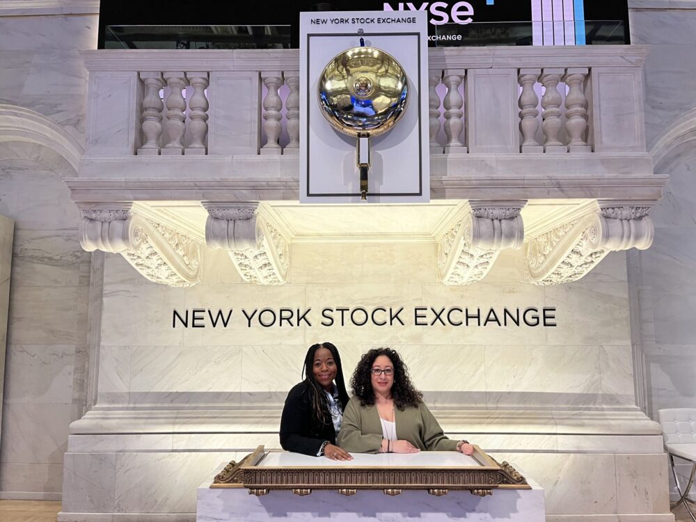 Two individuals posing for a photo at the new york stock exchange podium.