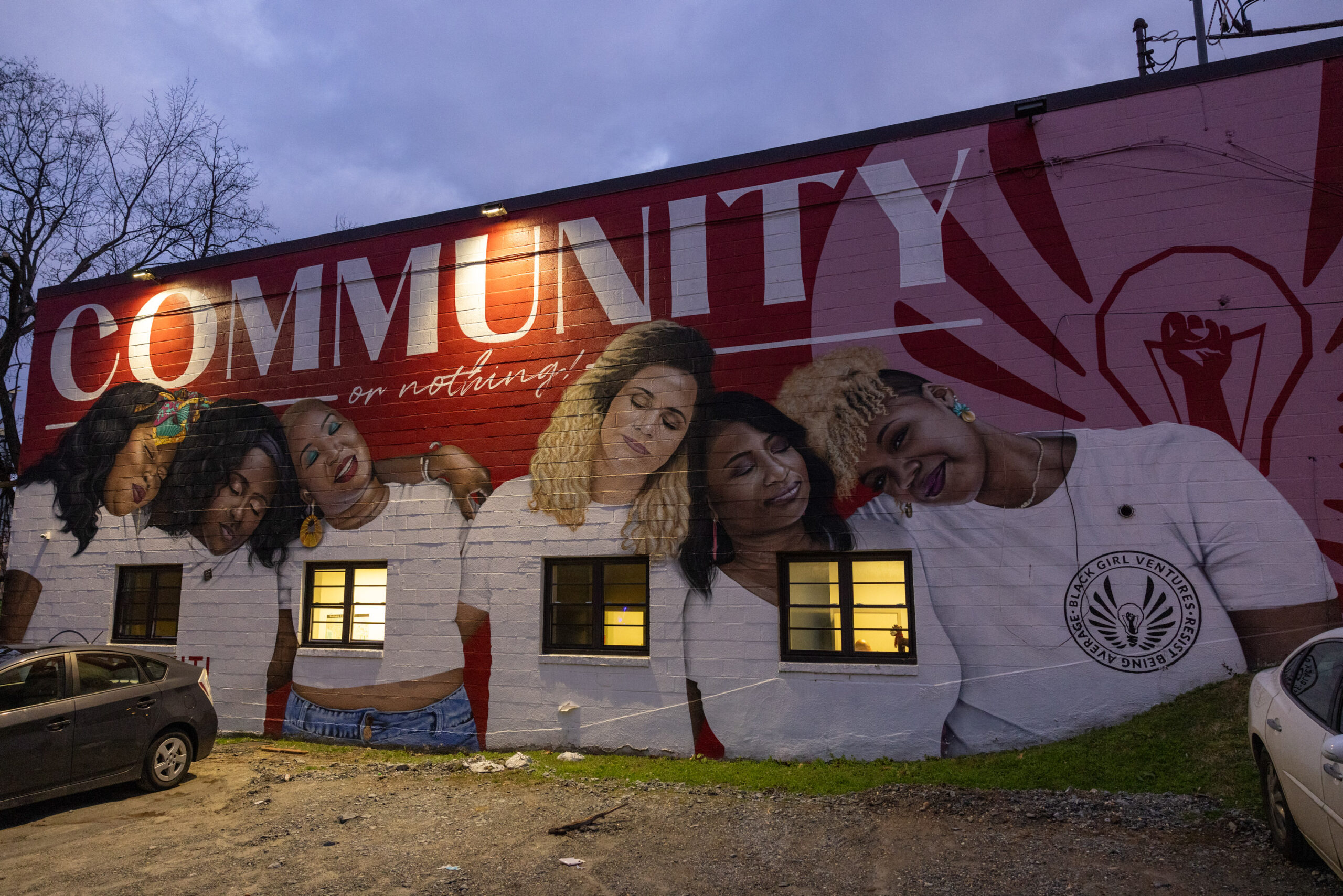 A vibrant mural on a building's side wall depicting several people with the word "community" painted in large white letters.