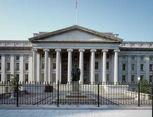 Grey stone US Treasury Department Building in front of blue sky