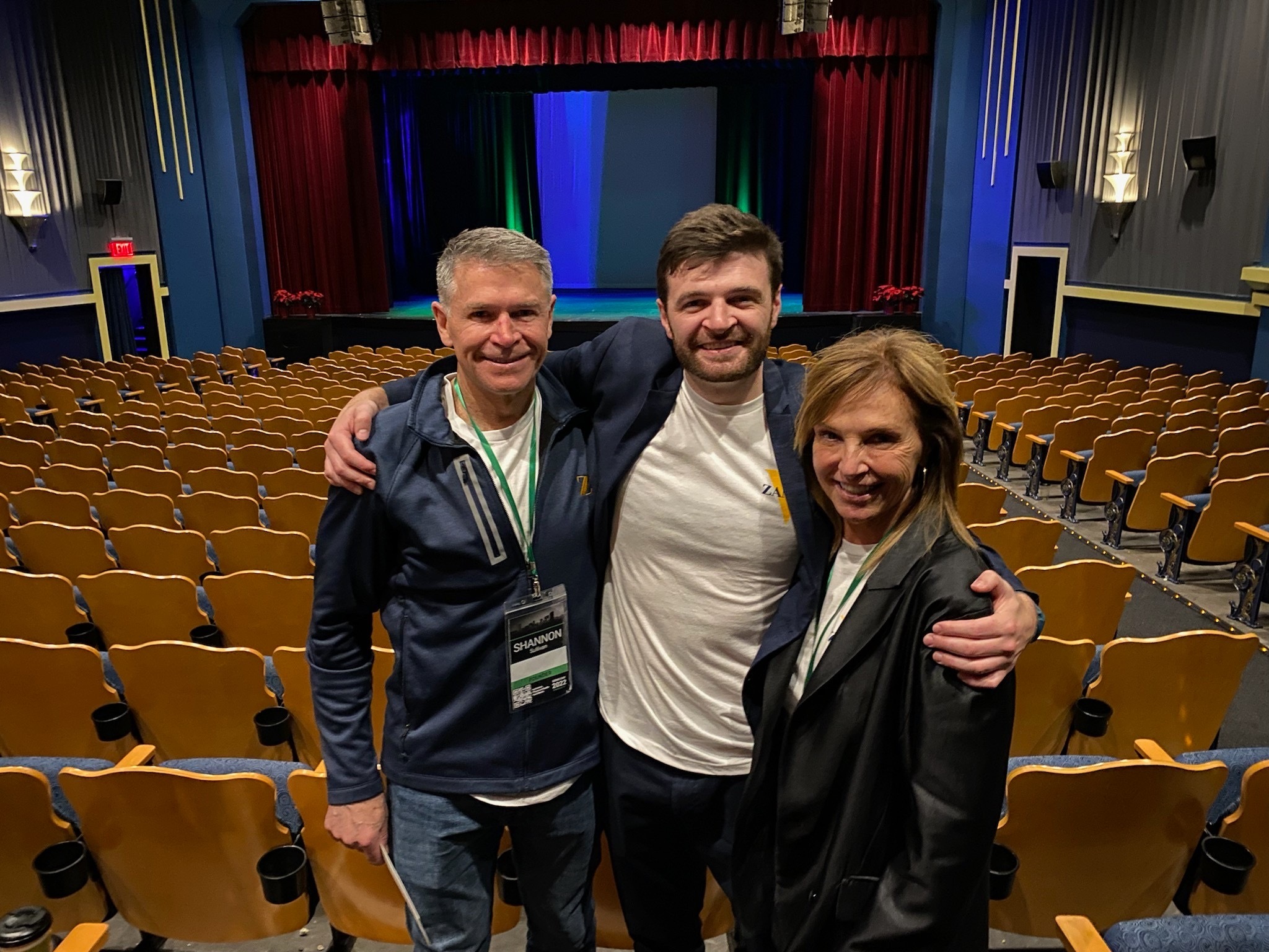 Three people posing for a photo in an auditorium