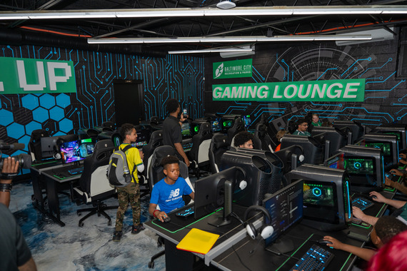 Young people inside esports lab with grey walls with blue and green detailing.
