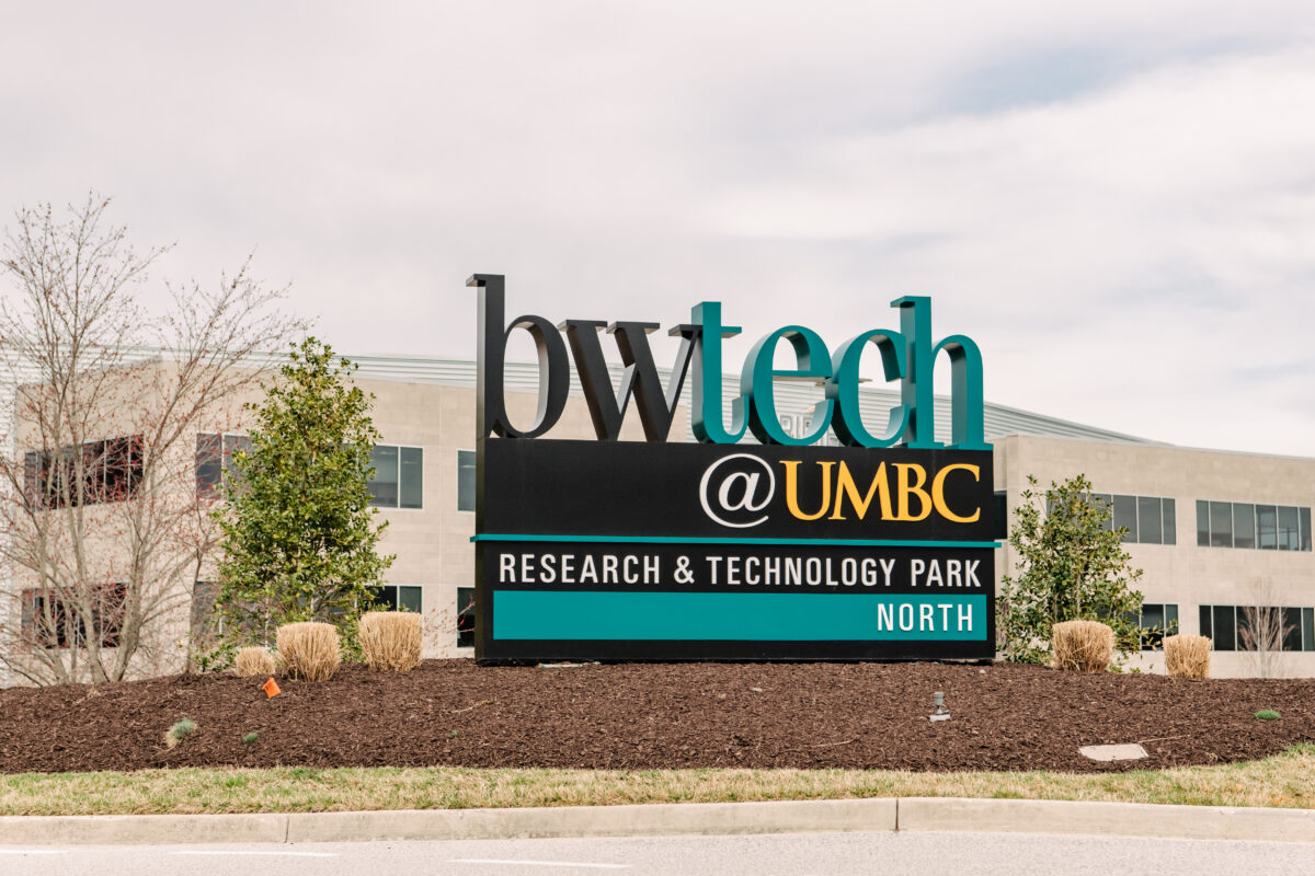 bwtech@UMBC signn in black, teal, yellow and white in front of brown office building