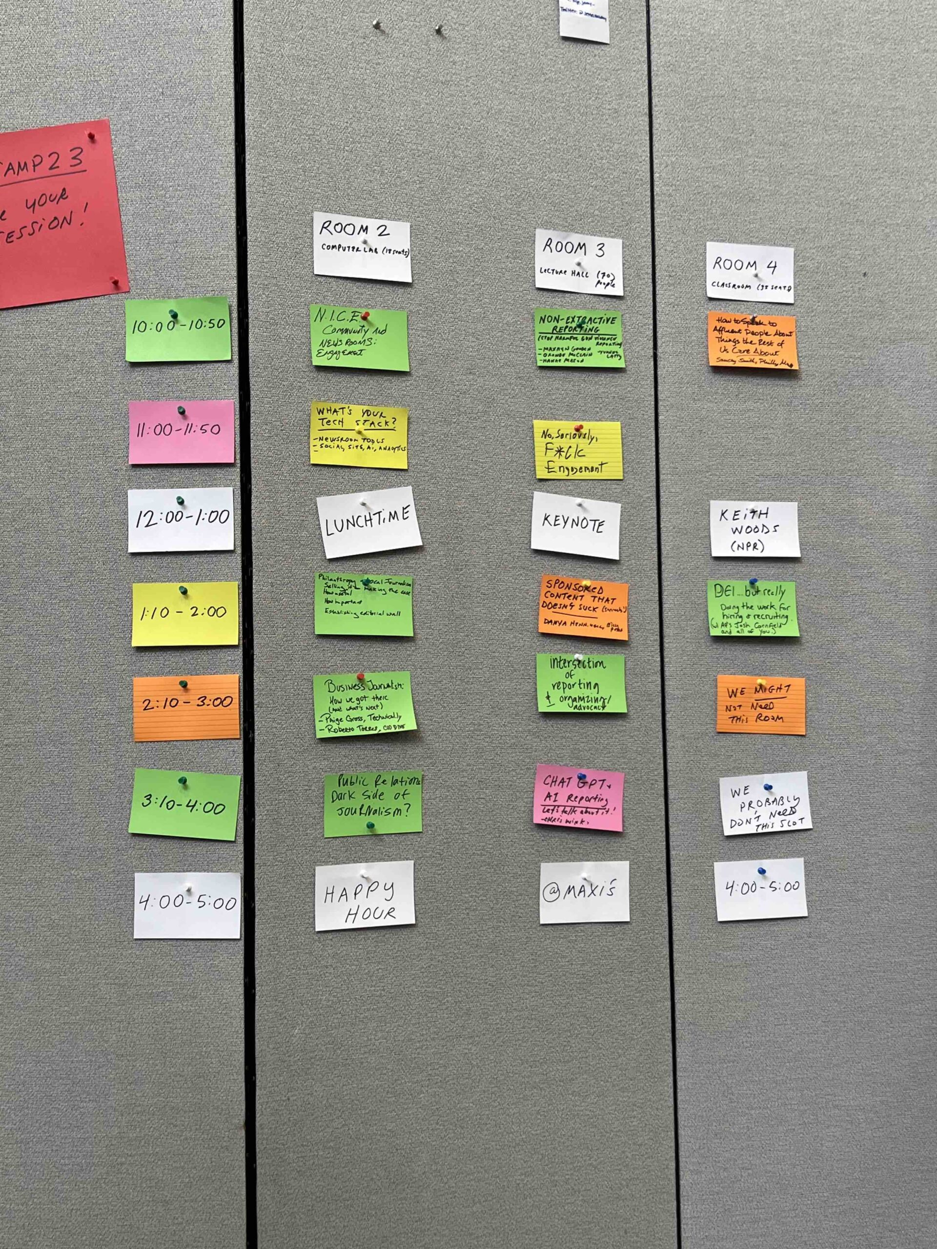 A schedule grid on a bulletin board showing hourly time slots and session topics on colored sticky notes for rooms 2, 3, and 4.