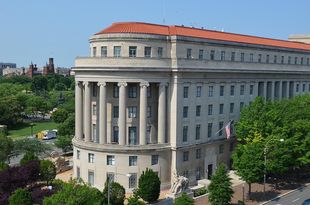 Grey Federal Trade Commission building with columns and red roof.