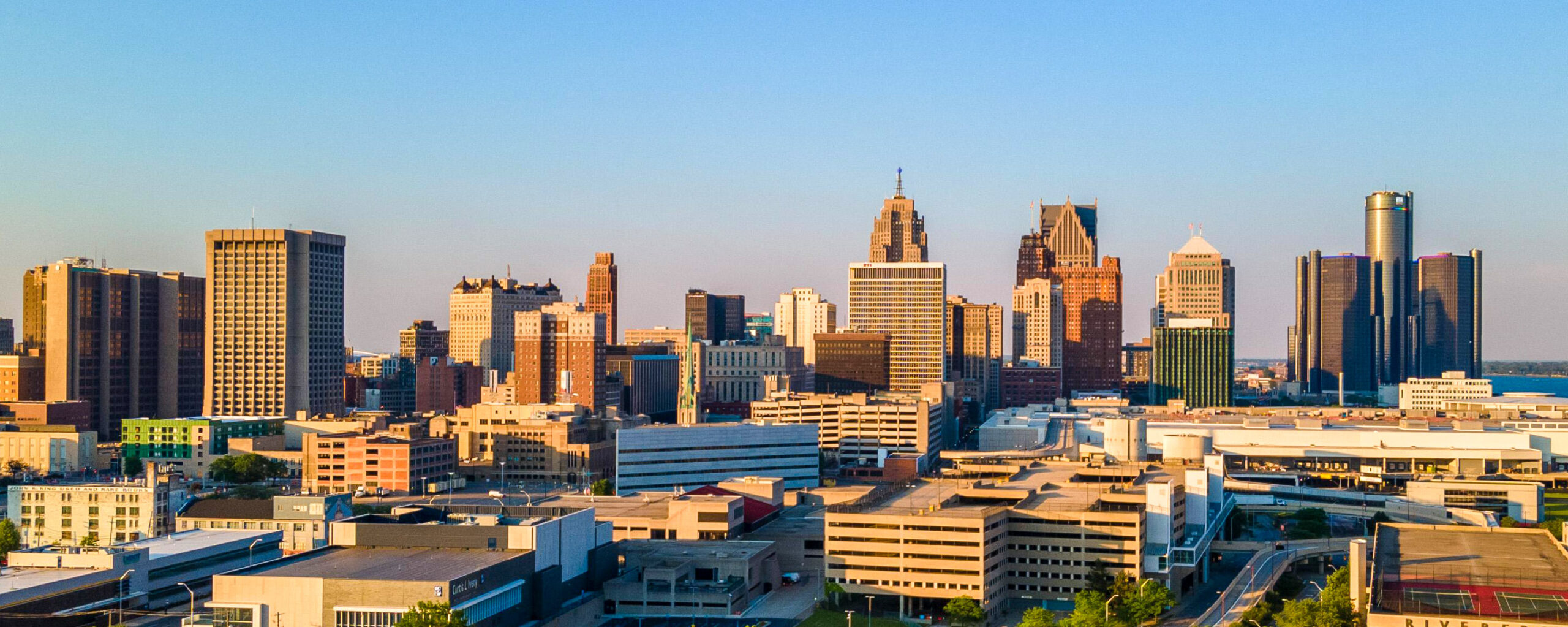 Aerial view of a city skyline with tall buildings under a clear blue sky, including modern skyscrapers and historic structures.