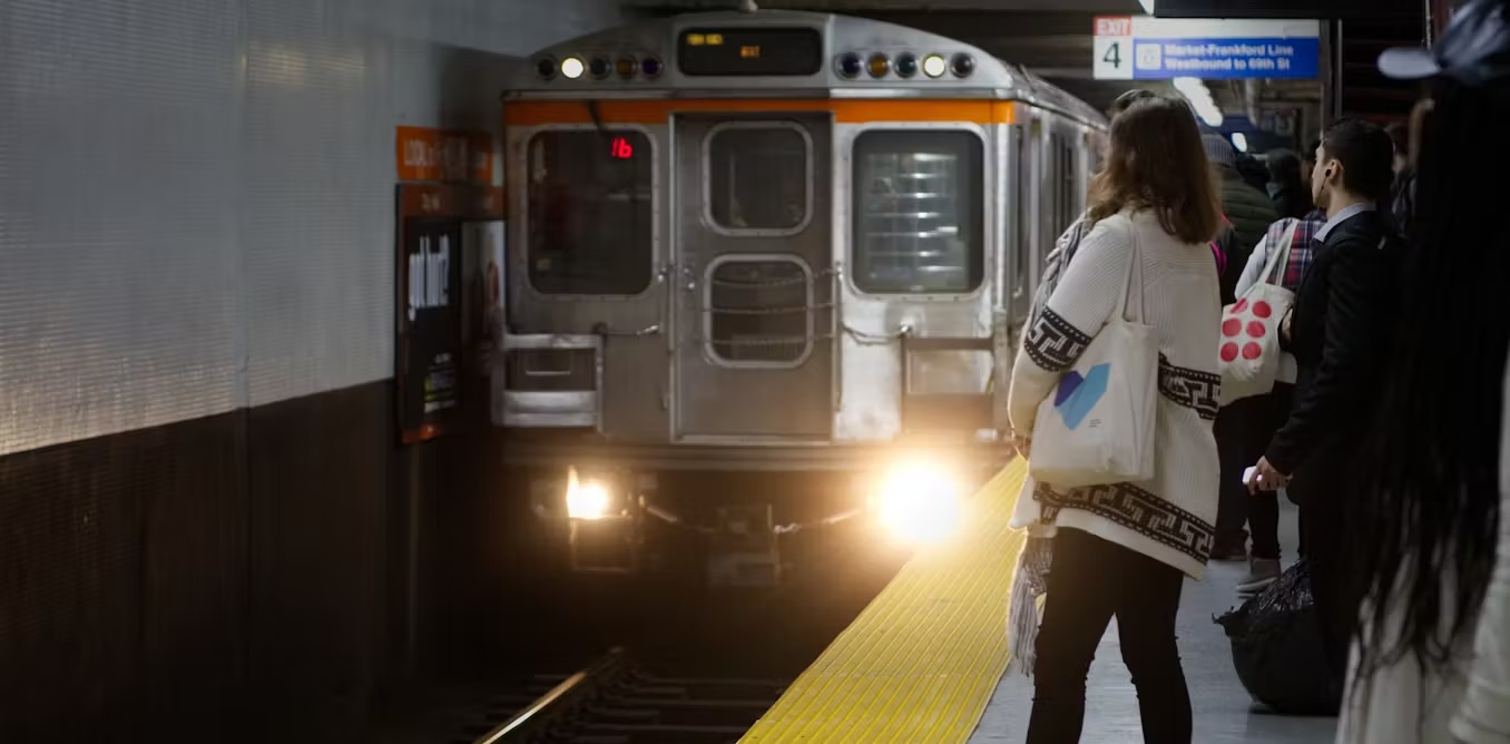 People waiting on a platform as a subway train approaches.
