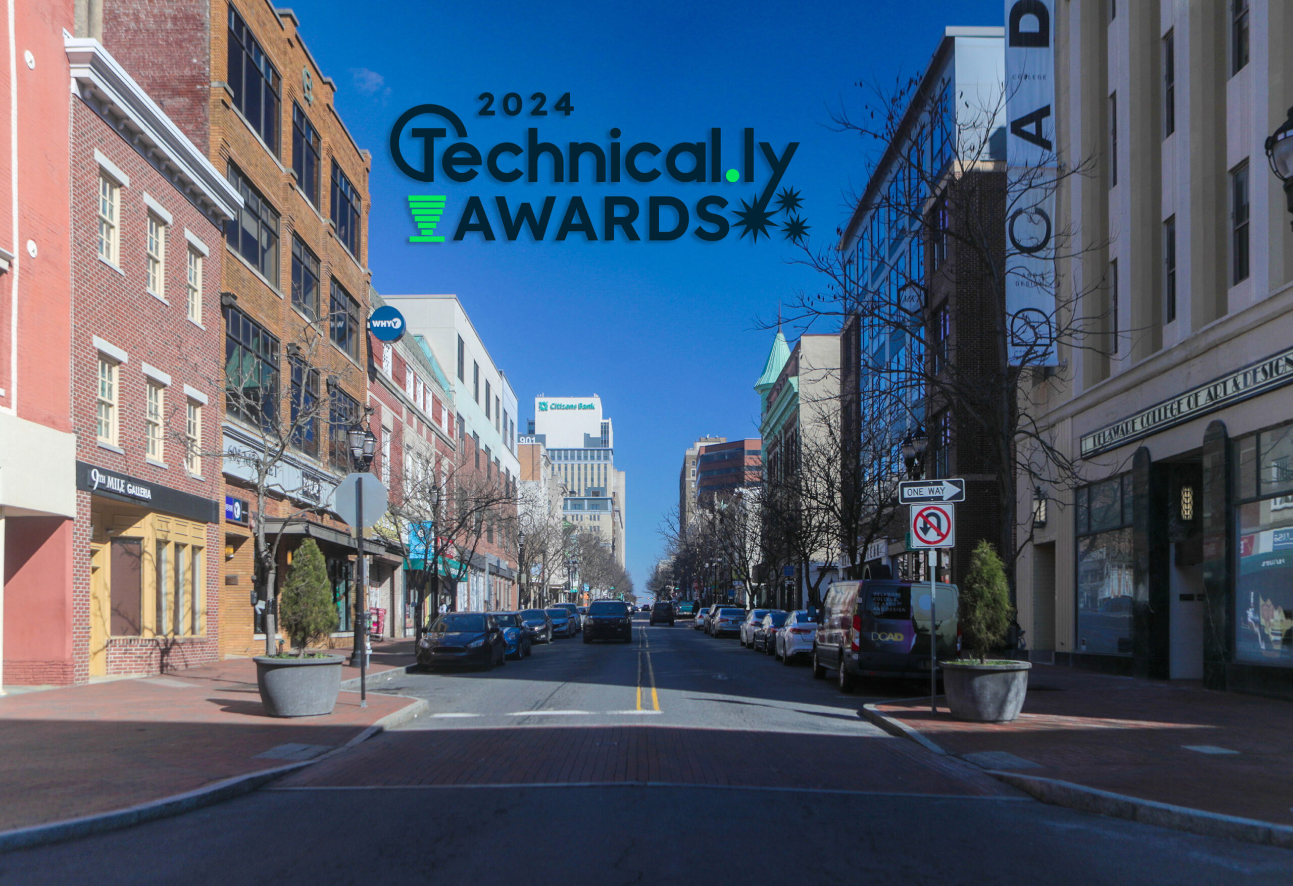 A city street with shops and buildings lining both sides and a "2024 Technically Awards" logo overlay at the top.