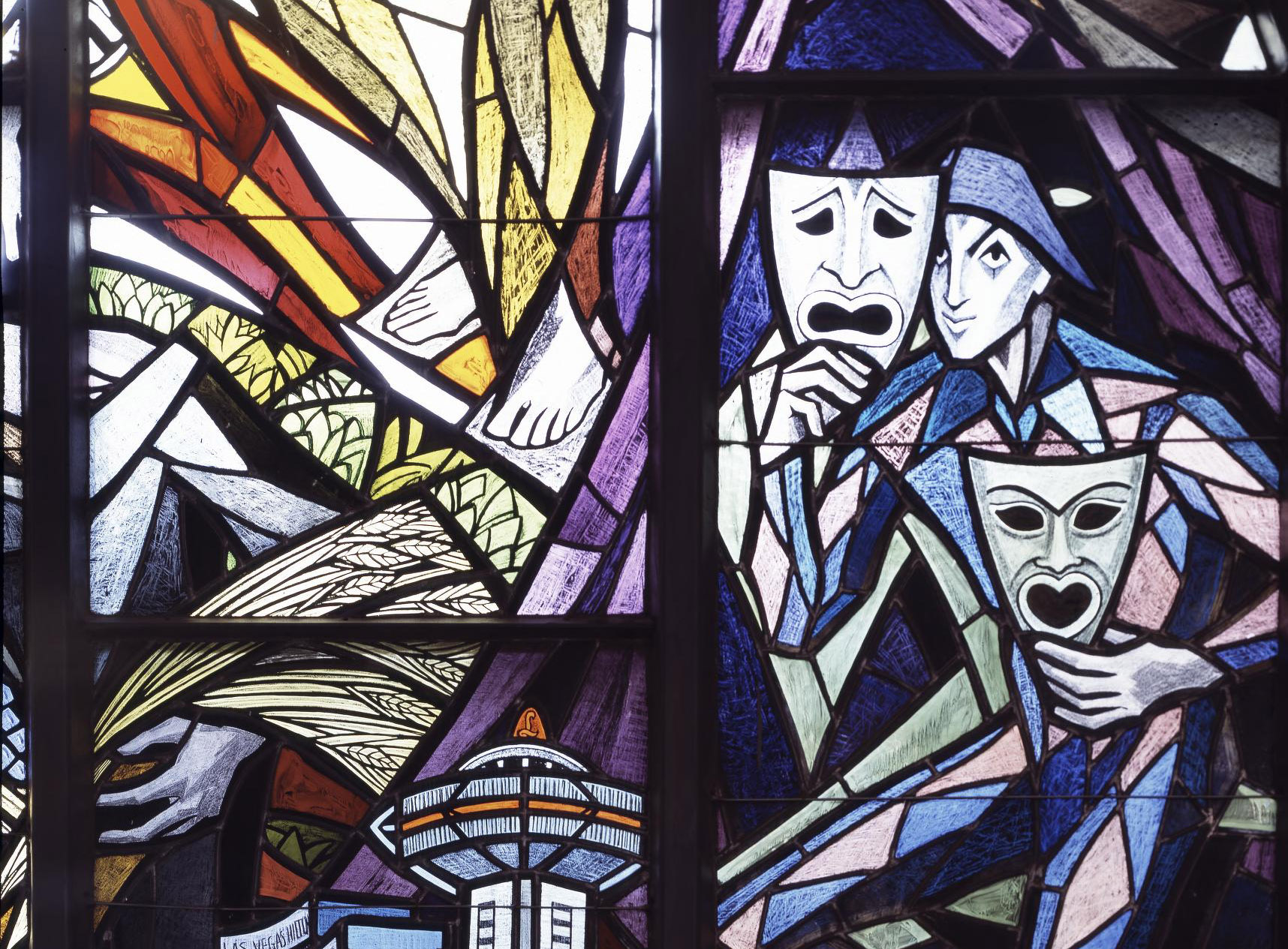 Stained glass window depicting abstract figures holding masks, colorful geometric shapes, and various elements including a tower and fields.
