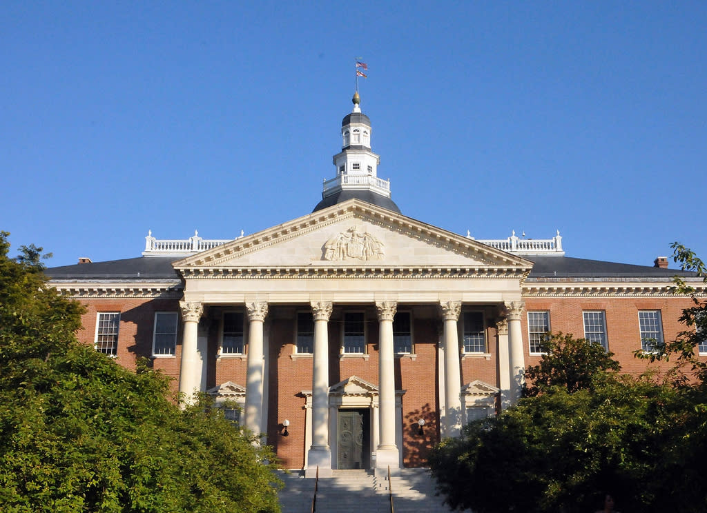 A large brick building with a white dome and columns, set against a clear blue sky.