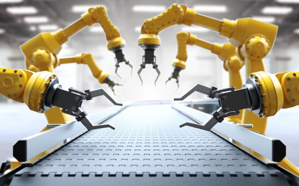 Robotic arms with grippers poised over a conveyor belt in an industrial setting.