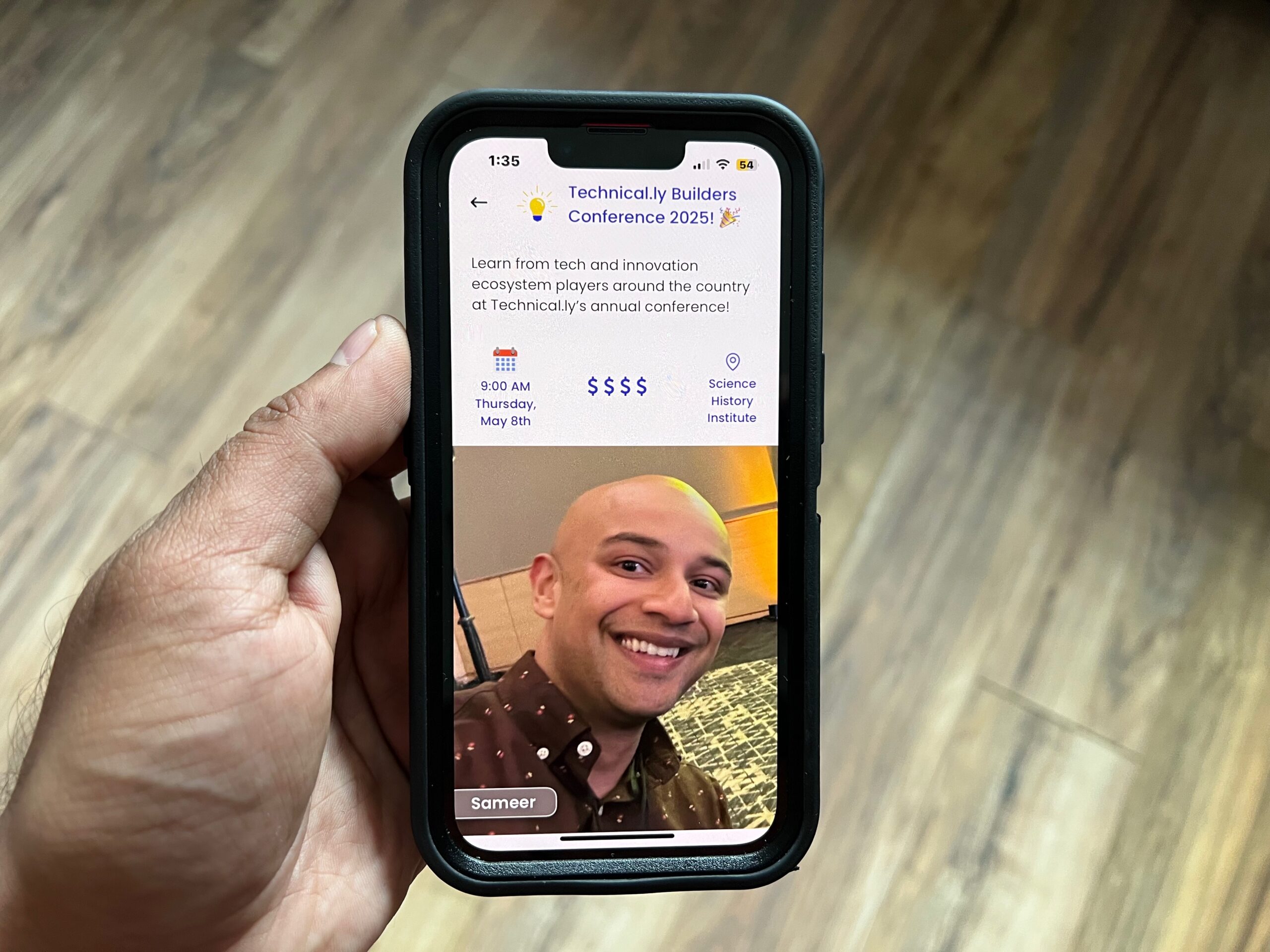 A hand holding a smartphone displaying a conference event app with a profile photo of a smiling person named Sameer and event details for "Technically Builders Conference 2025.