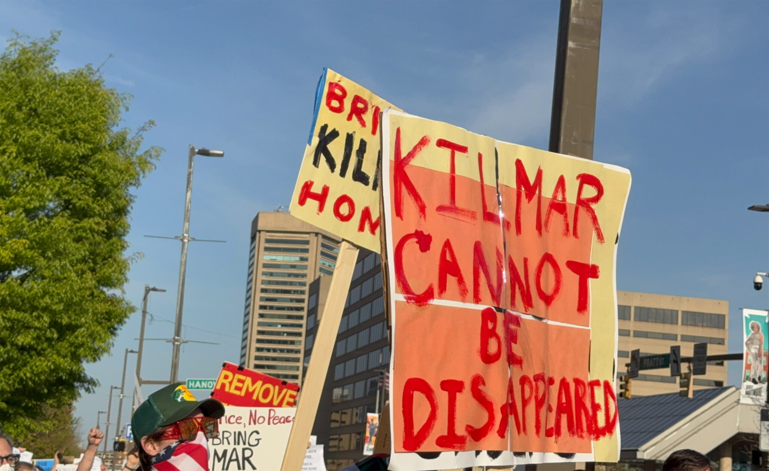 Protesters hold signs that read "KILMAR CANNOT BE DISAPPEARED" and "BRING KILMAR HOME" during a daytime demonstration in an urban area.