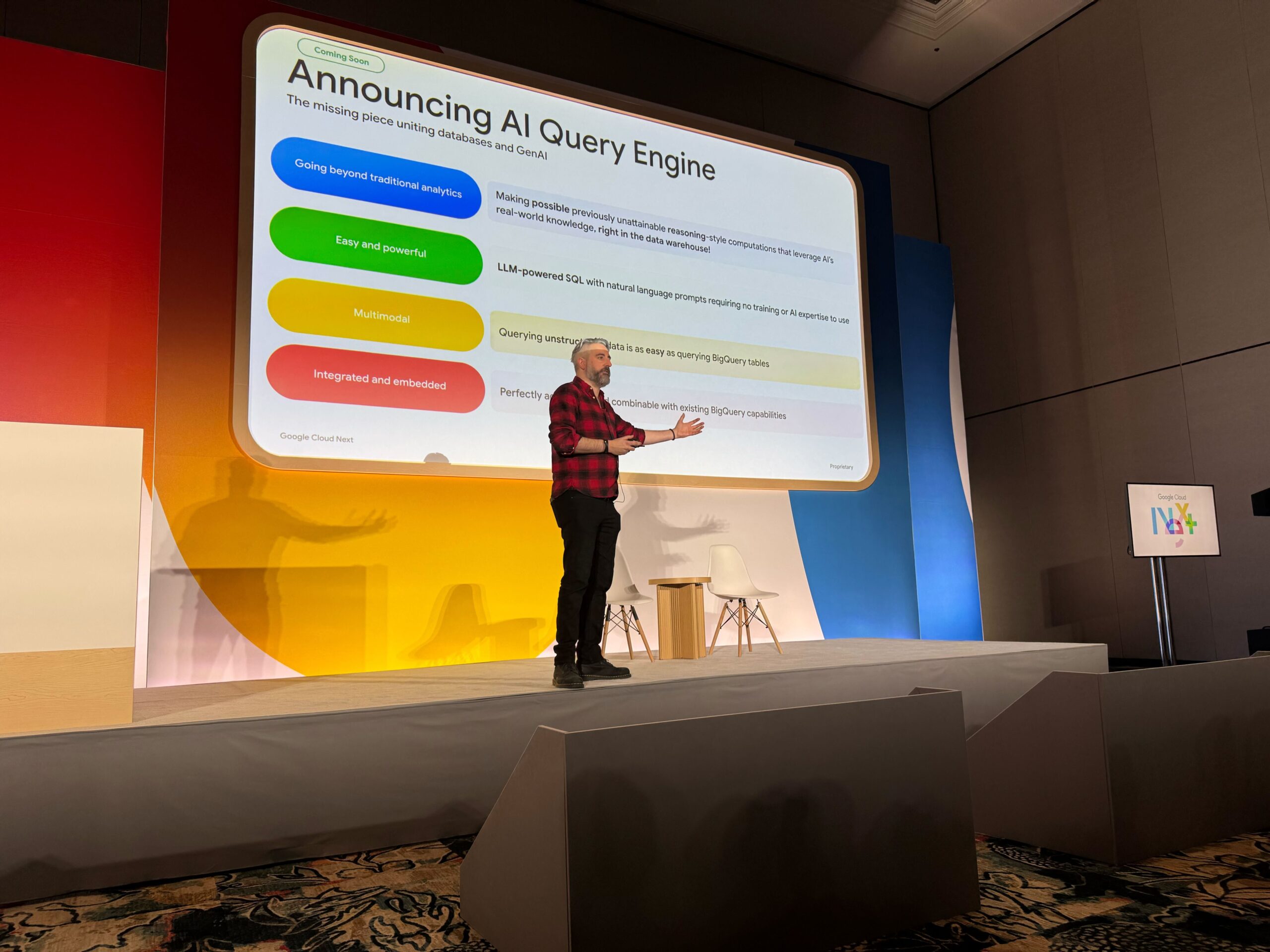 A person stands on stage presenting a slide titled “Announcing AI Query Engine,” detailing its features, at a conference or tech event.