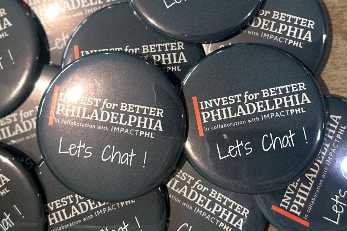 A pile of round buttons with the text "INVEST for BETTER PHILADELPHIA in collaboration with IMPACTPHL" and "Let's Chat!" written on them.