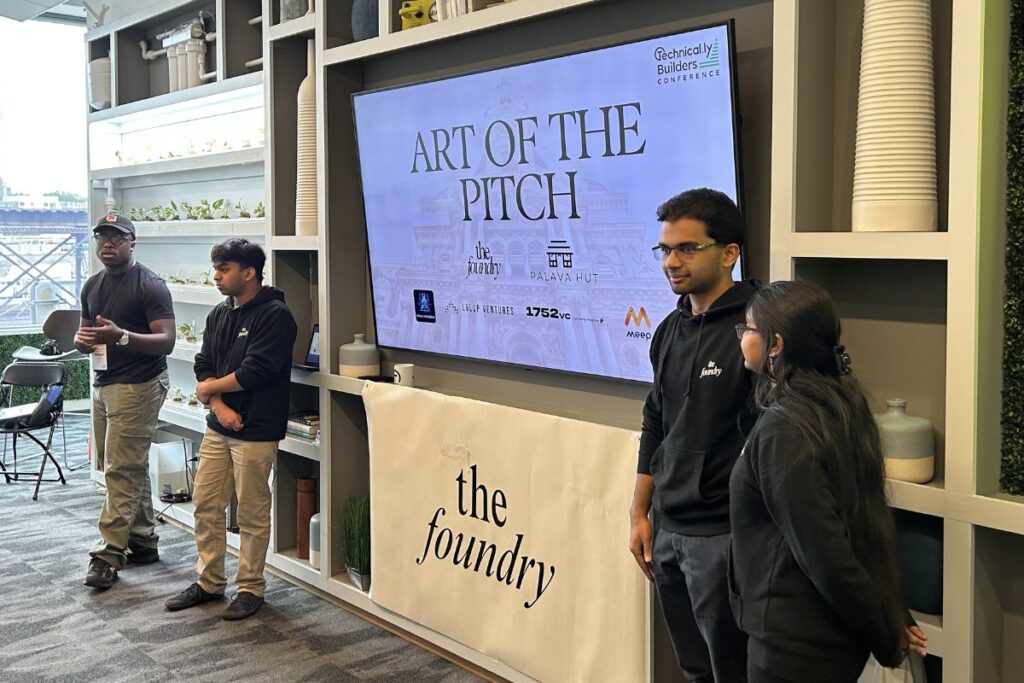 Four people stand near a large screen displaying "Art of the Pitch" at The Foundry, with logos of event sponsors visible on the screen.