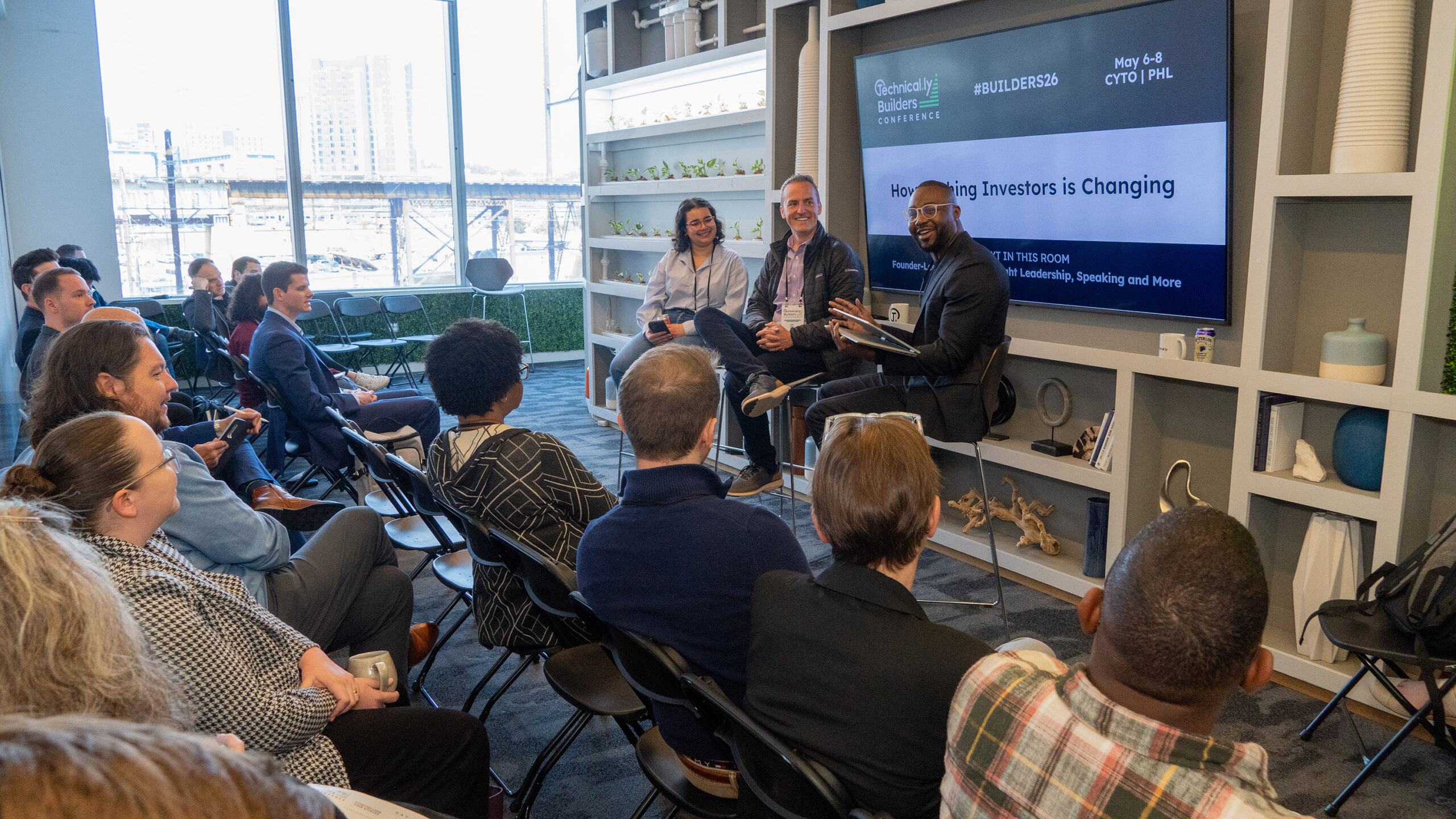 Three panelists speak to an audience at a business conference, with a presentation slide behind them reading "How Pitching Investors is Changing.