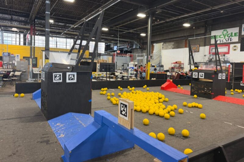 Yellow balls sit between two hoops on a practice playing field for robotics competitions.