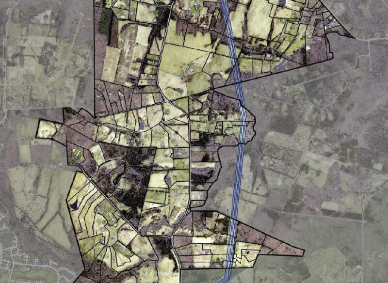 Aerial map showing divided plots of land, outlined in black, with a blue line representing a river or stream running vertically through the center.