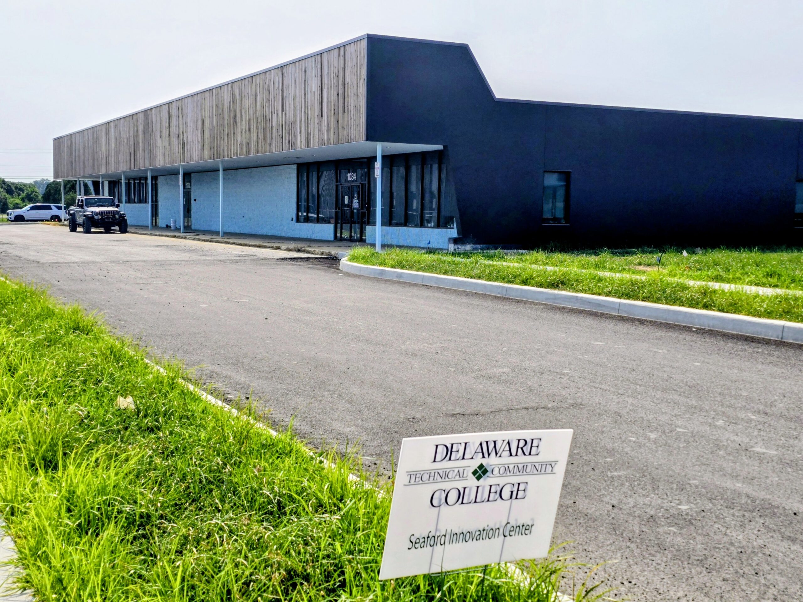 A modern, single-story building with a sign in front reading "Delaware Technical Community College Seaford Innovation Center." A black SUV is parked near the entrance.