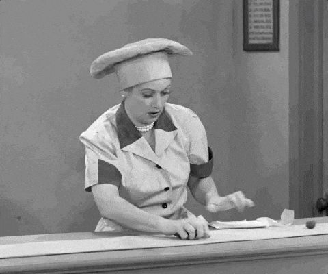 Scene from I Love Lucy with Lucille Ball in a chef’s uniform hurriedly wrapping chocolates on a conveyor belt, struggling to keep up as the belt speeds up.