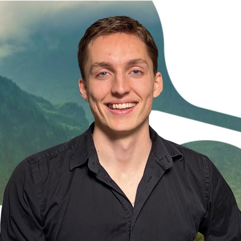 Young man with short brown hair, wearing a black button-up shirt, smiling at the camera with a scenic mountain and abstract background.