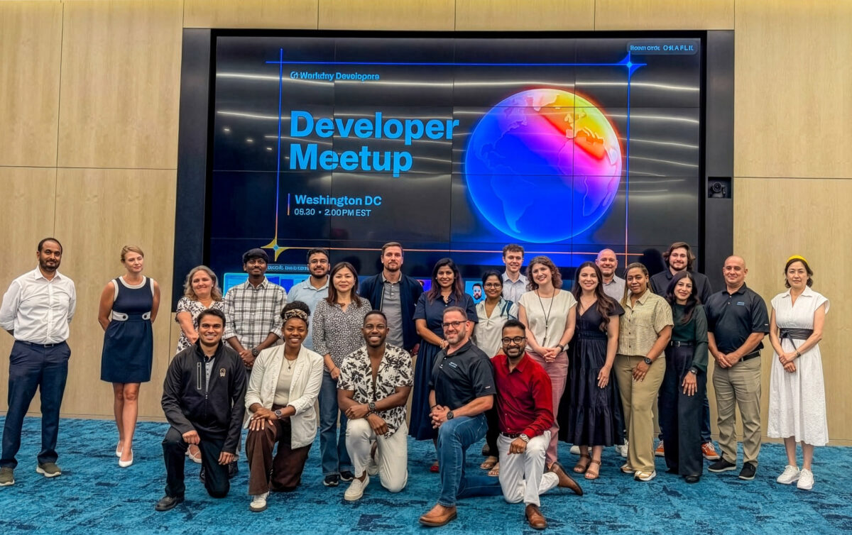 A group of people posing for a photo in front of a large screen displaying "Developer Meetup, Washington DC, 6:30 - 2:00 PM EST.