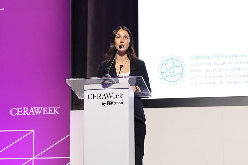 A woman speaks at a podium labeled “CERAWeek by S&P Global” with a presentation slide and purple CERAWeek branding in the background.