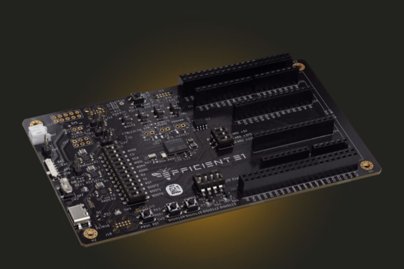 A black printed circuit board labeled “EFFICIENT1,” featuring multiple connectors, electronic components, and a USB port, placed on a dark background.