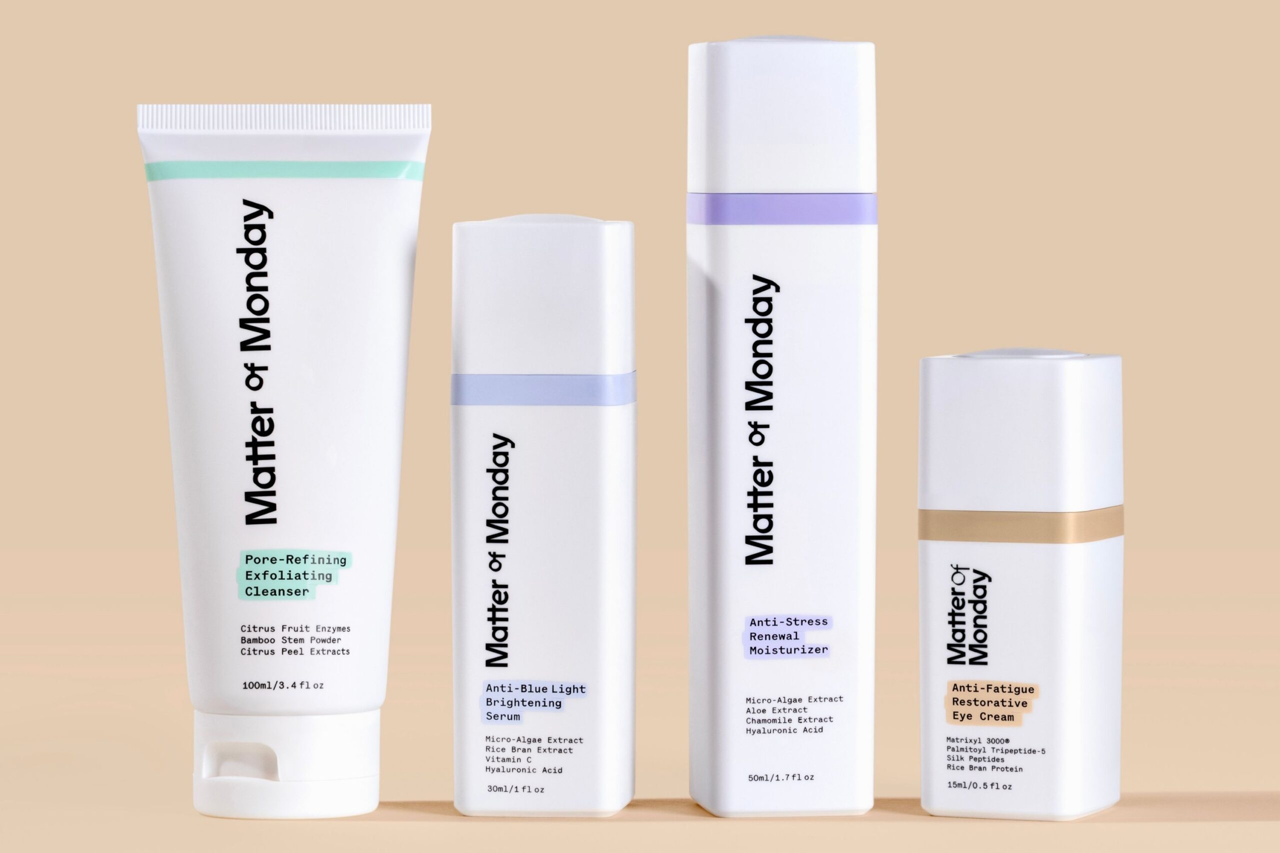 Four Matter of Monday skincare products stand in a row against a beige background, including a cleanser, brightening serum, moisturizer, and eye cream.
