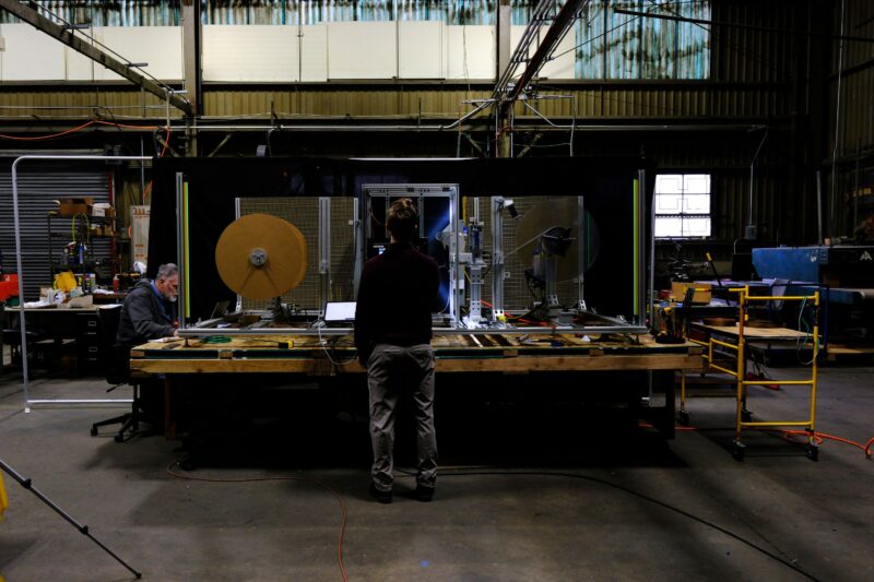A person stands in front of a manufacturing roll being inspected (Courtesy)