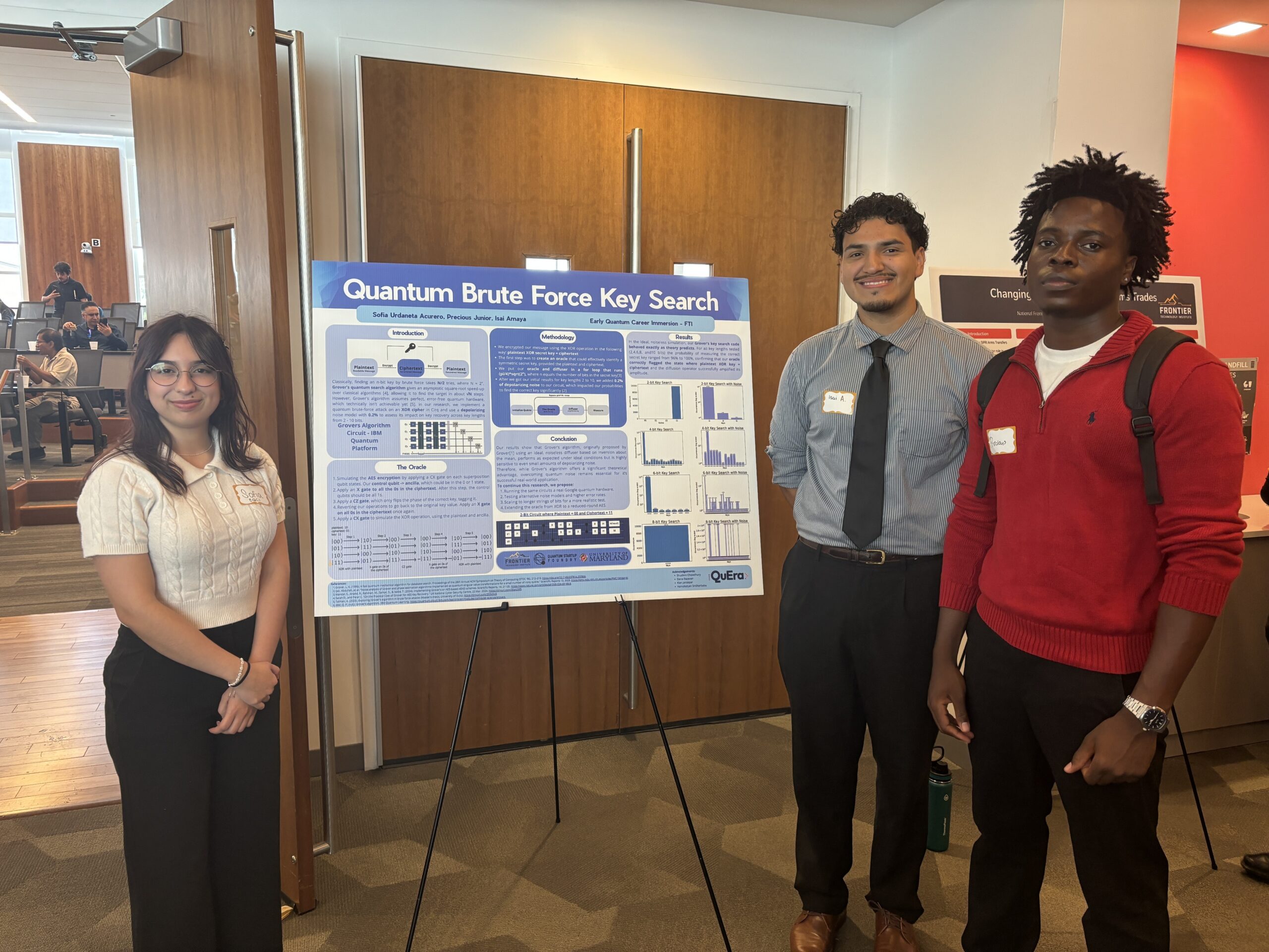 Three students stand beside a scientific poster titled “Quantum Brute Force Key Search” in a conference room setting.