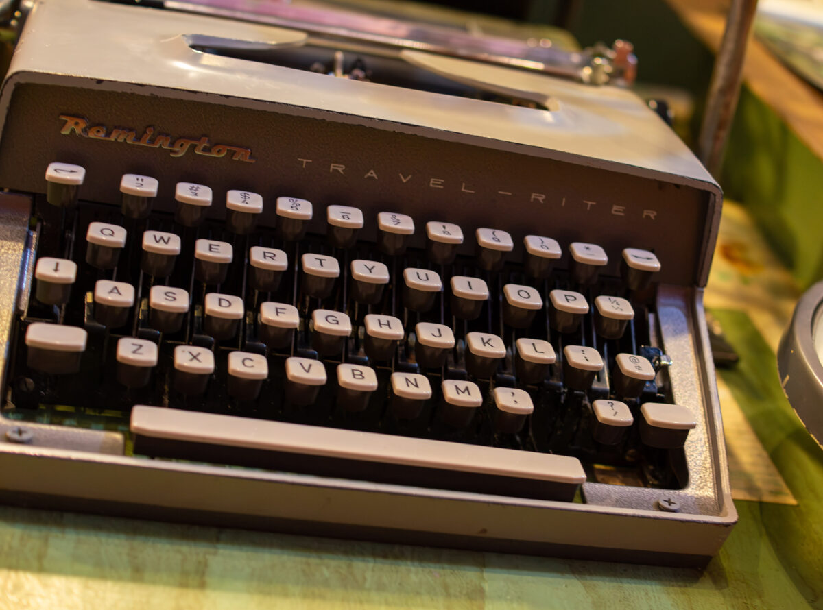 Close-up of a vintage Remington Travel-Riter typewriter with black and white keys, sitting on a green surface.