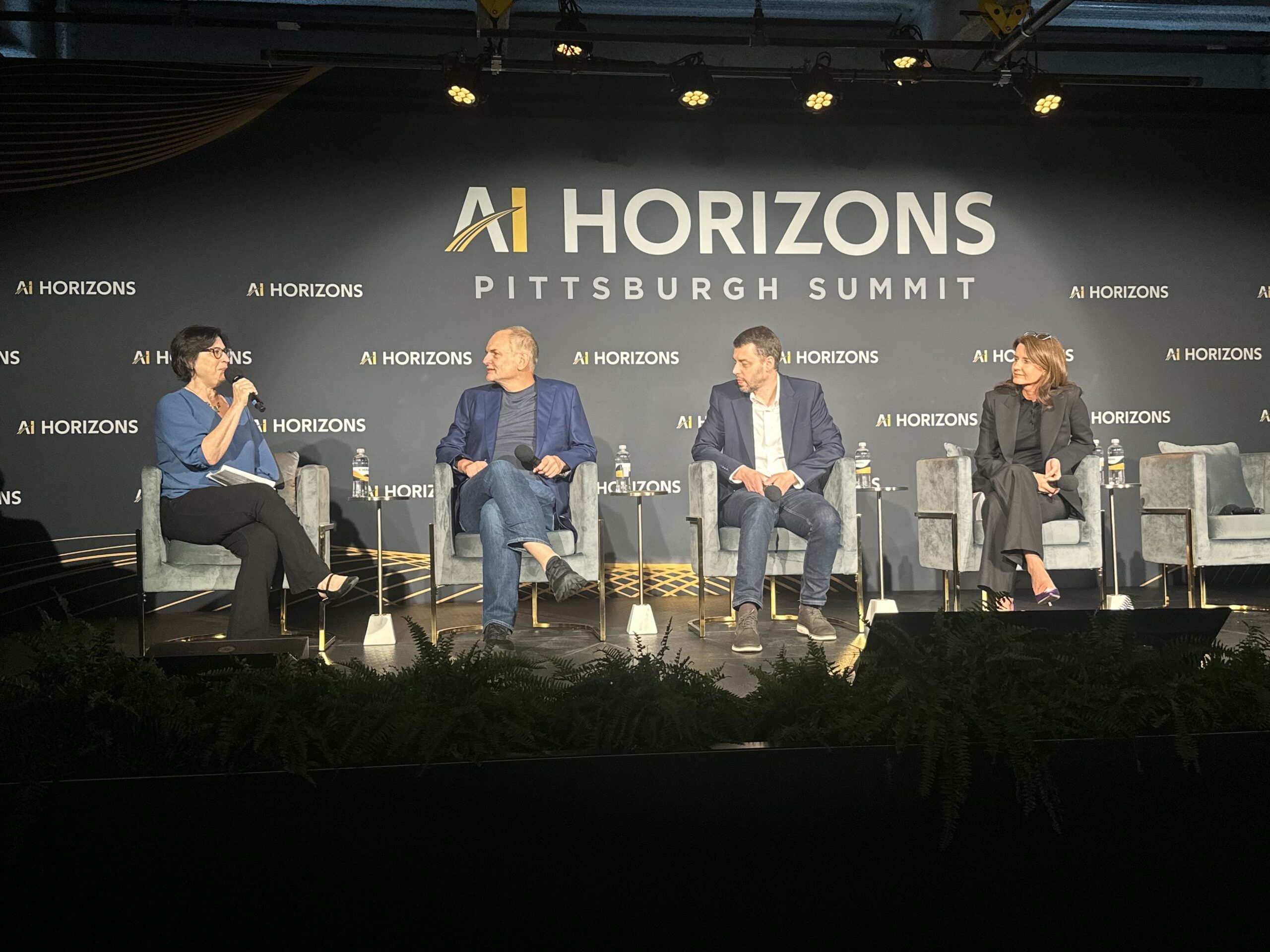 Four people sit on stage having a panel discussion at the AI Horizons Pittsburgh Summit, with the event logo displayed on the backdrop behind them.