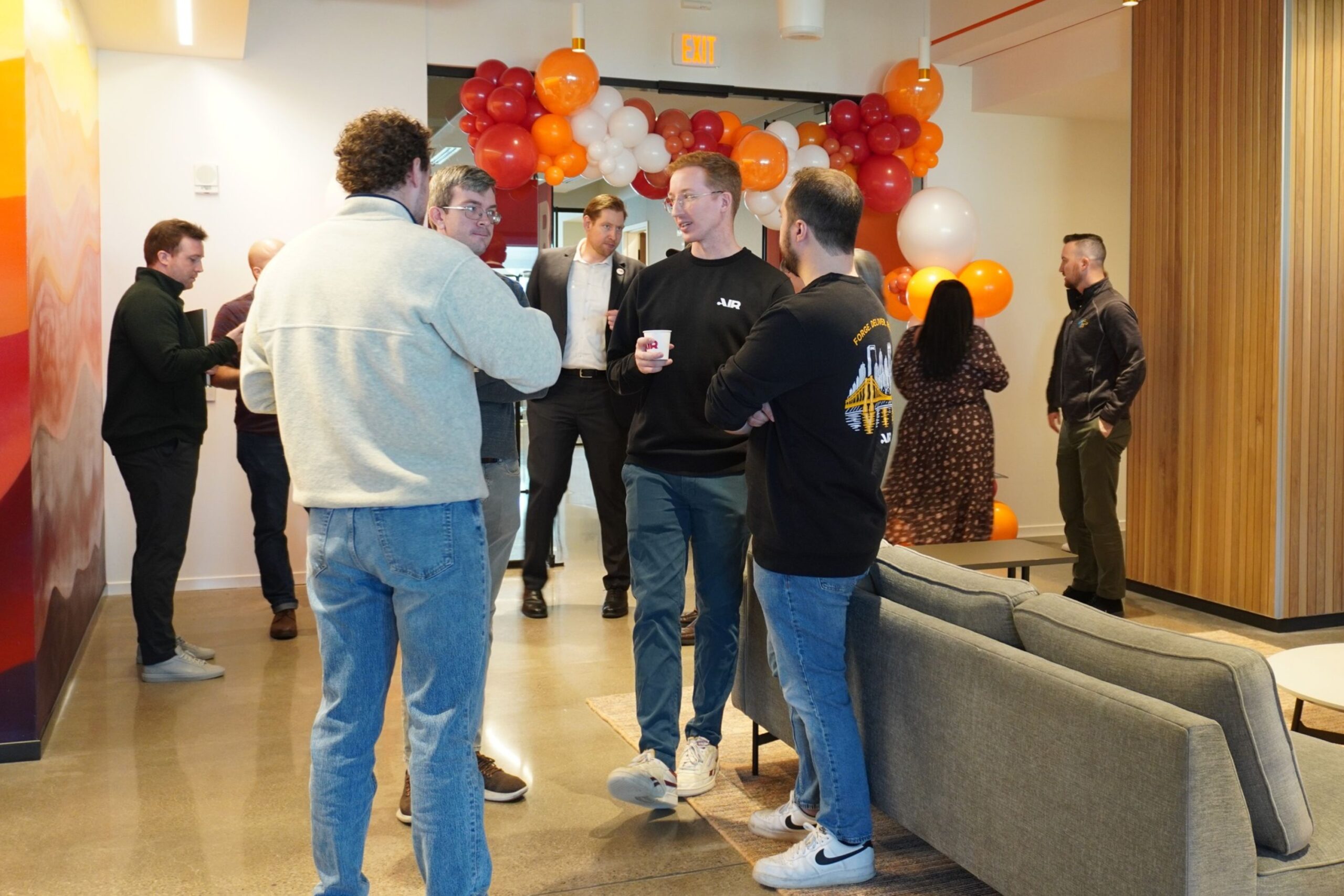A group of people talking in an office decorated with red and orange balloons.