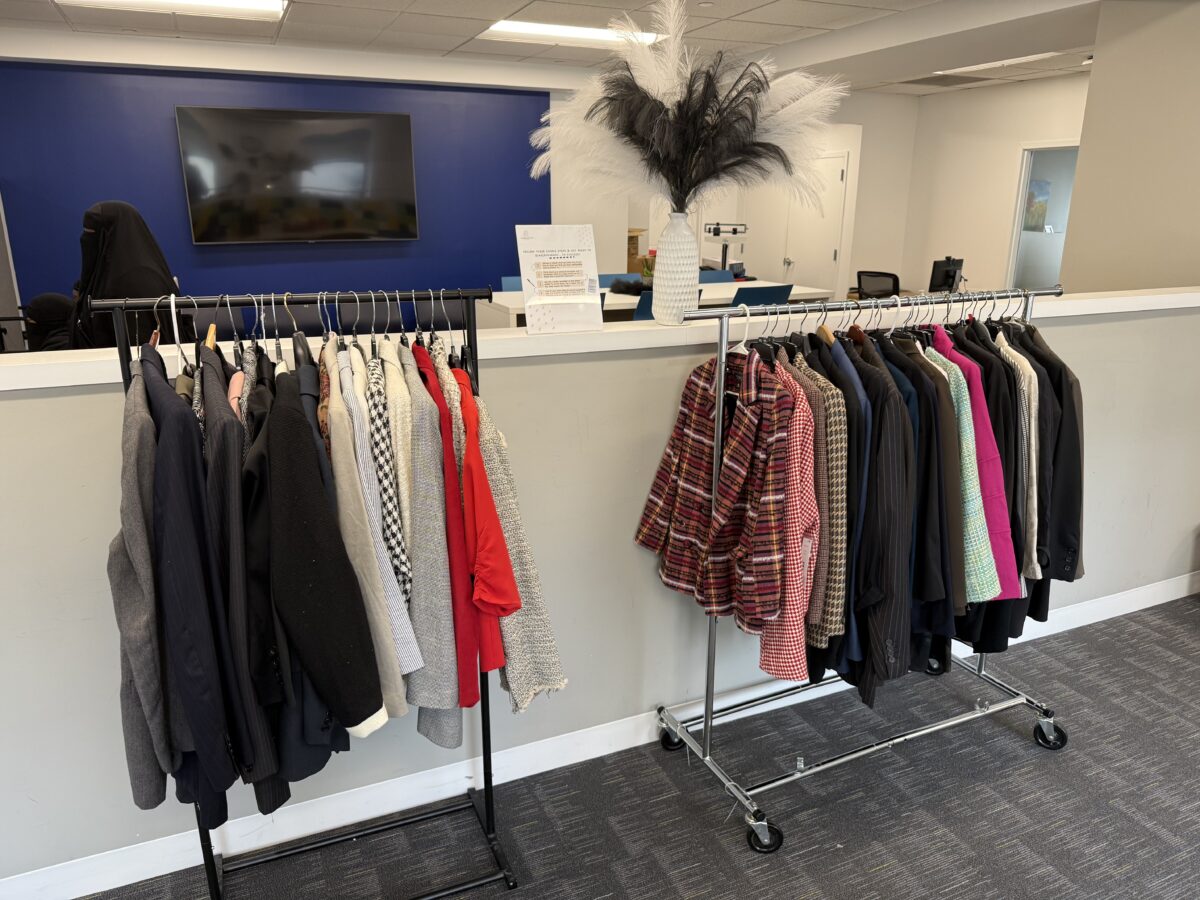 Two rolling garment racks holding various blazers and jackets in an office space.